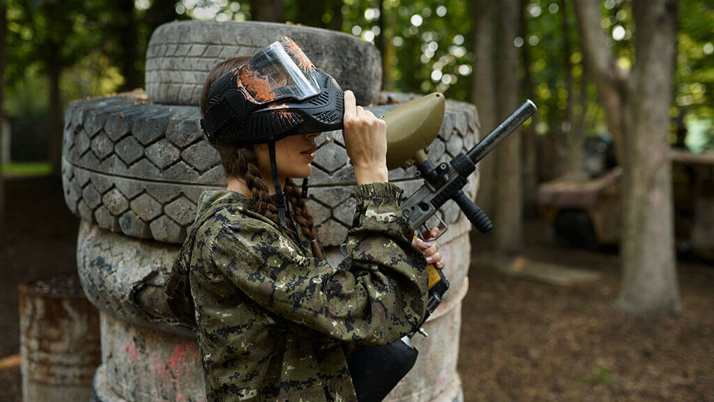 Female paintball player on playground in forest