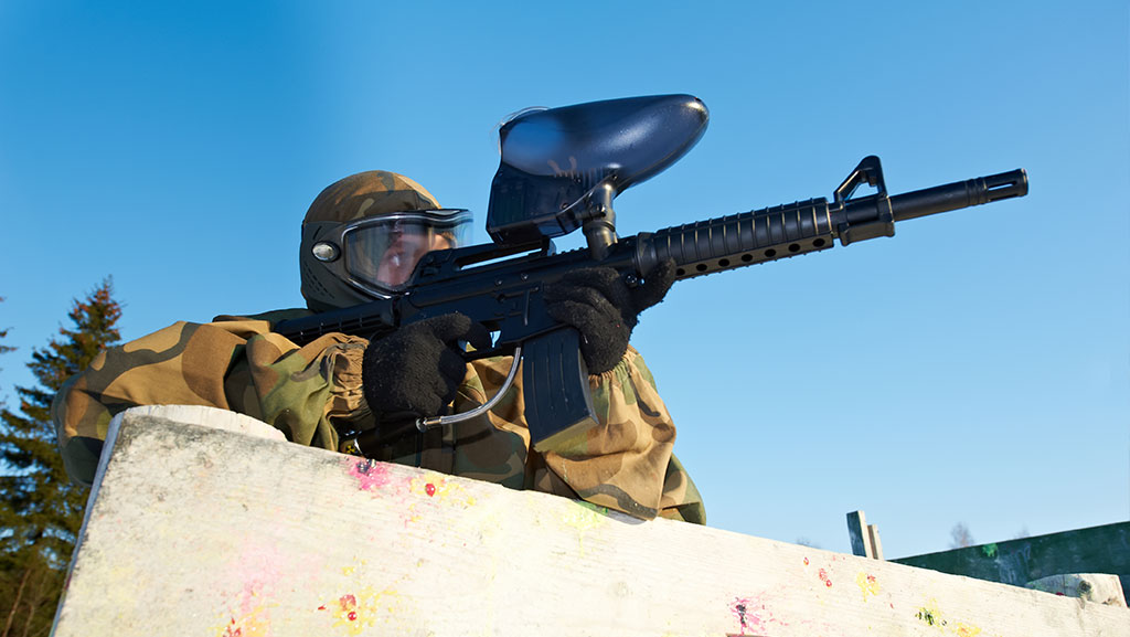 Paintball player with marker at winter outdoors