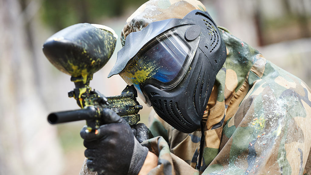 Paintball player with marker at winter outdoors