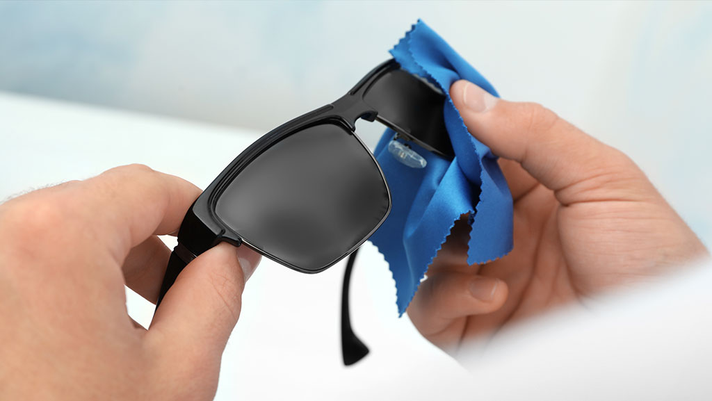 Man wiping sunglasses with microfiber