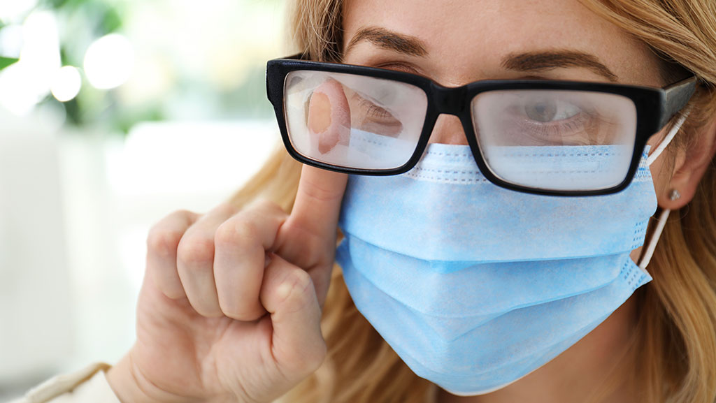 Woman wiping foggy glasses caused by wearing Mask